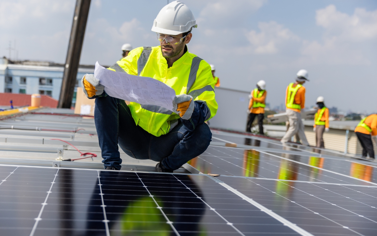 A Man In A Safety Vest And Hardhat Looking At A Paper